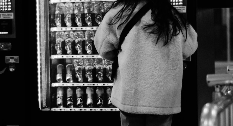Une personne devant une machine de distributeur automatique